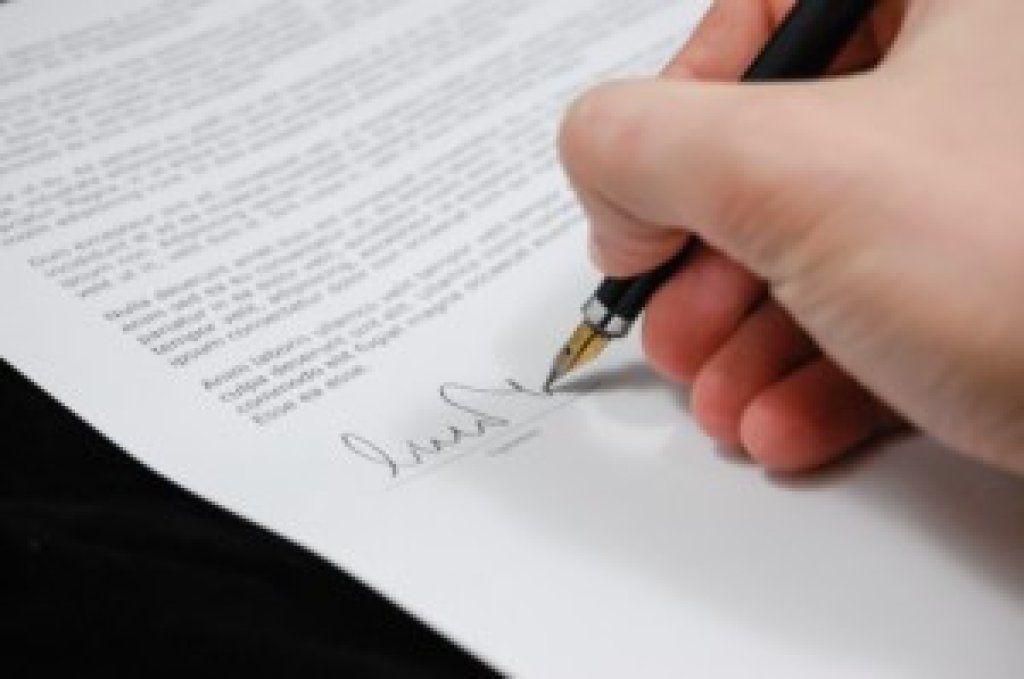 A person is signing their signature on an important document.