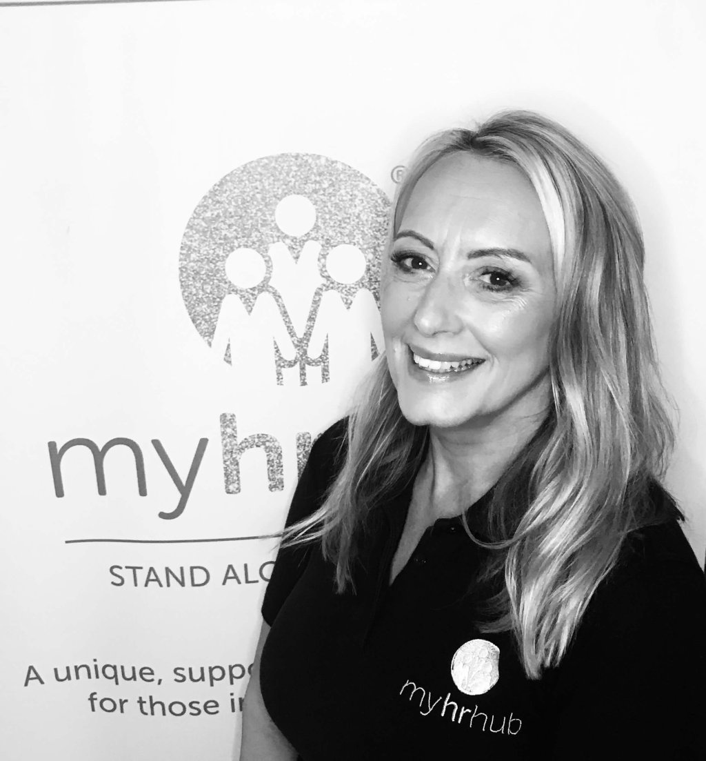 My HR Hub founder, Rebecca Bull, is stood next to a HR event banner.